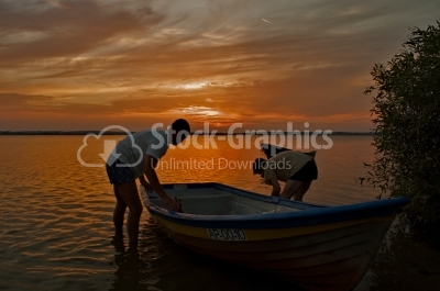 2 men at sunset with boat