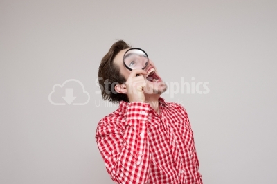 Excited man looking through a Magnifying Glass