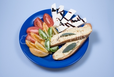 Fresh tomatoes, chees and bread on a blue plate