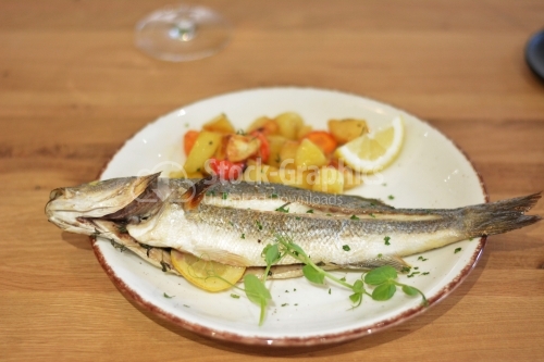 Fried trout fish with potato and pepper garnish.