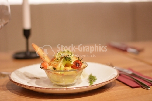 Glass bowl with au gratin potatoes, broccoli, tomatoes and wheat grains.
