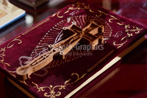 Holy gospel with red velvet cover. The holy carved wooden cross