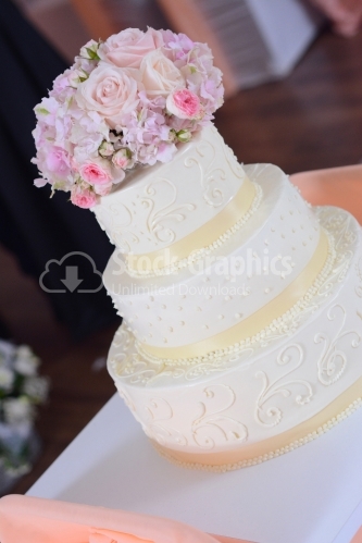 Ivory-colored wedding cake with a flower bouquet on top