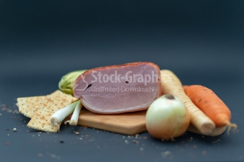 Prague ham on wooded cutboard with onion carot and cucumeber