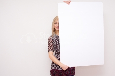 Pretty female student posing behind a white panel isolated on wh