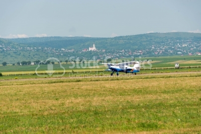 Propeller Plane landing on the field sideways view