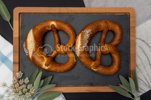 Two brezel side by side with green leaves