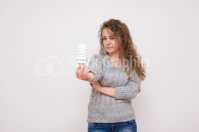 Woman holding an energy saving lightbulb - isolated over white