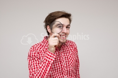 Young guy looking throug a magnifying glass