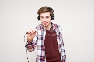 Young man in headphones holding jackplug in his hand isolated on