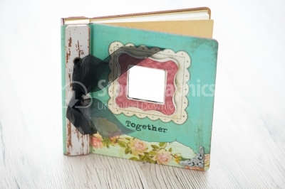 A photo album sits on a rustic wooden background
