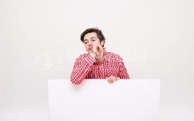 A smiling handsome male posing behind a white panel isolated 