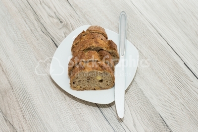 Bread cut sliced â€‹â€‹on a white plat, with knife
