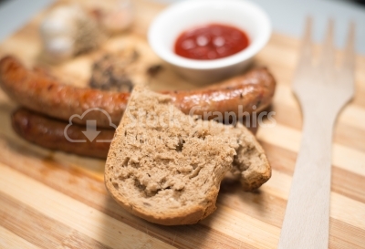 Bread sitting on roasted sausage