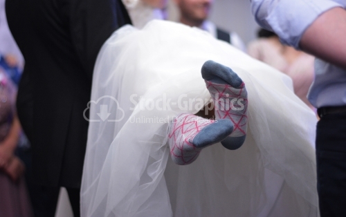 Bride with wool socks standing. The bride is held in her arms by a man.
