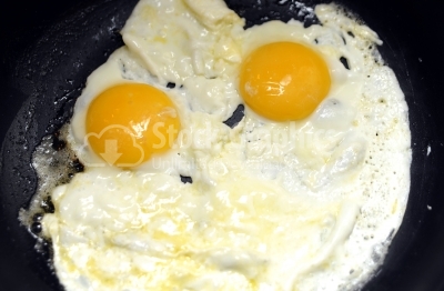Close-up photo of two scrambled eggs in black frying pan