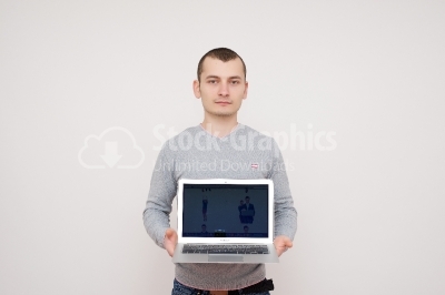 Confident young man with laptop standing over white background. 