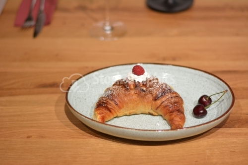 Delicious croissant with cream and raspberries. For breakfast.
