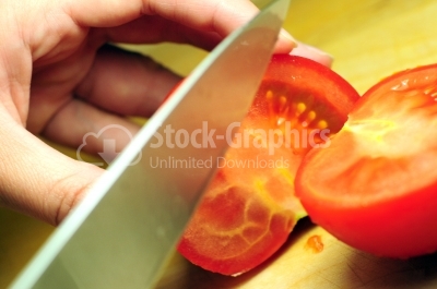 Female hands with knife, cutting fresh red tomatoes