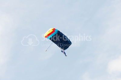 Low-angle skydiver flying on colorful parachute