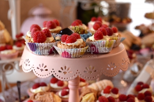 Mini tarts with whipped cream and raspberry placed in drawn paper. Candy bar