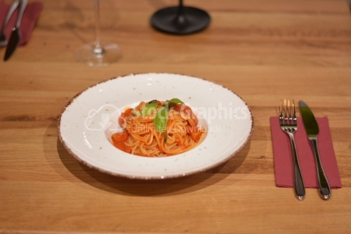 Pasta with tomato sauce decorated with basil.