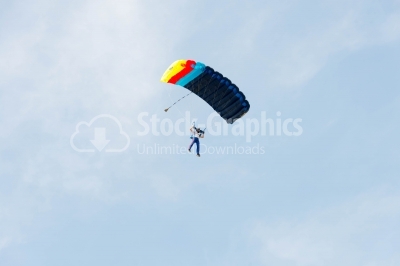 Skydiver flying with colorful parachute on the blue sky