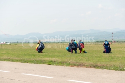 Skydivers with parachutes land on ground