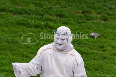 Street artist playing disguised as a white statue