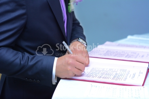 The groom signs the marriage documents.