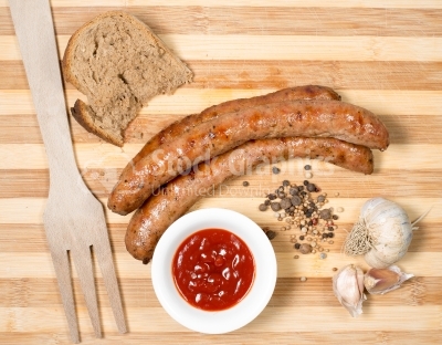 Top view of grilled sausages with ketchup, bread and garlic