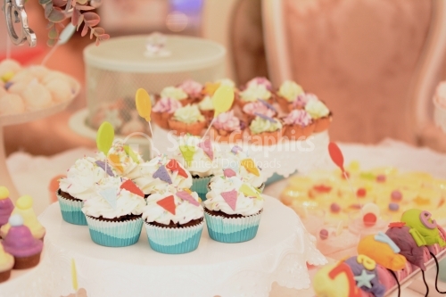 White cream muffins decorated with colorful triangular marzipan. Candy bar