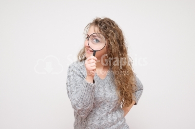 Woman look through magnifying glass and smile 