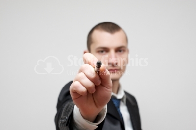 Young businessman pointing with the pen at you.