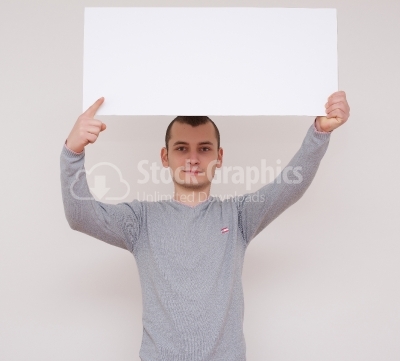 Young man holding a white panel above his head isolated on white