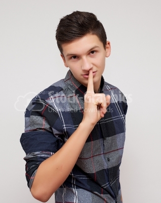 Young man holding finger over mouth gesturing silence