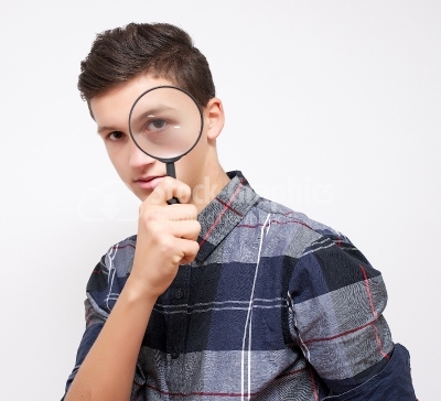 Young man is looking through magnifier