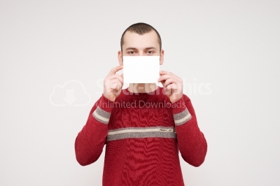 Young man with an empty sheet of paper half covering face stock 